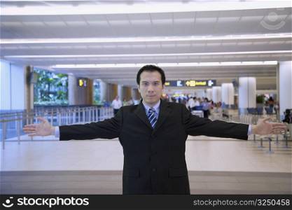 Portrait of a businessman standing in a airport lounge with his arms outstretched