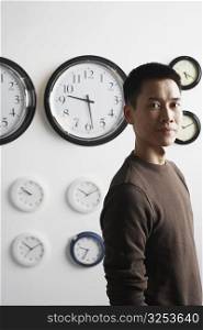 Portrait of a businessman standing in front of clocks on the wall