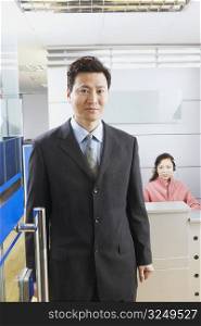 Portrait of a businessman standing in office with a receptionist behind him