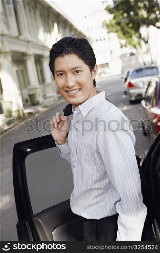 Portrait of a businessman standing near a car and smiling
