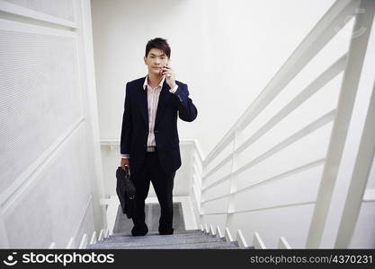 Portrait of a businessman standing on a staircase and talking on a mobile phone