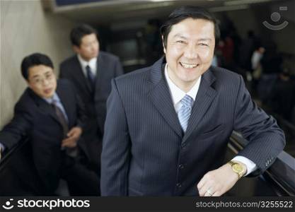 Portrait of a businessman standing on an escalator smiling