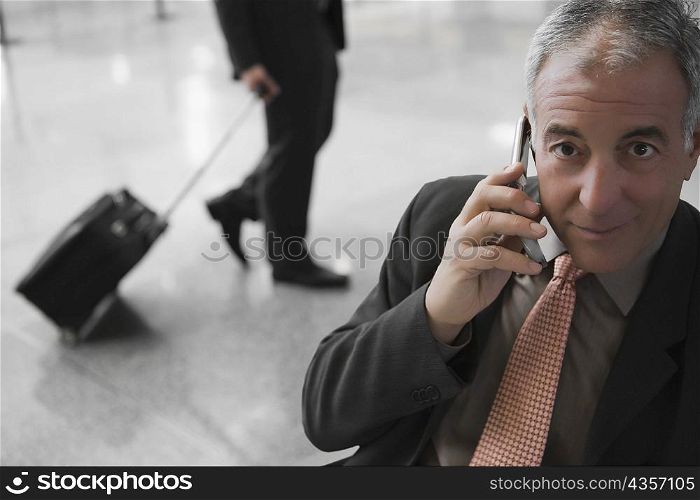Portrait of a businessman talking on a mobile phone at an airport