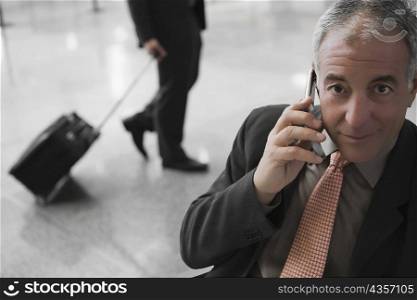 Portrait of a businessman talking on a mobile phone at an airport