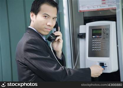 Portrait of a businessman talking on a public phone