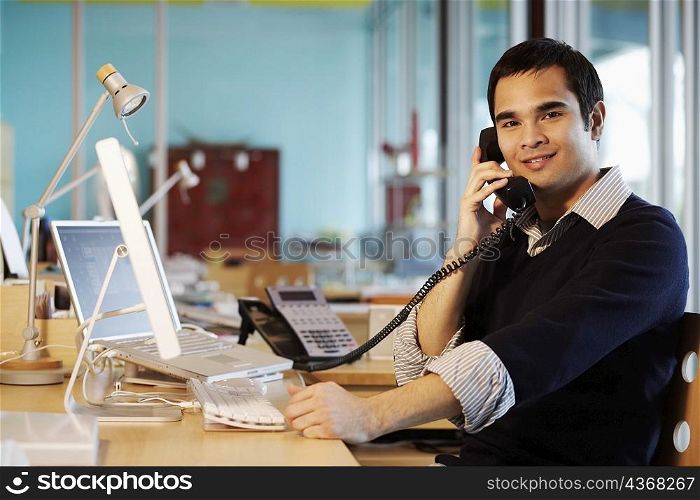 Portrait of a businessman talking on the telephone in an office and smiling