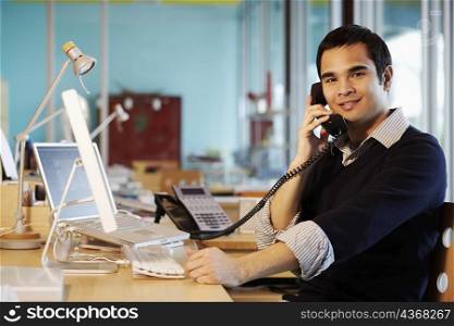 Portrait of a businessman talking on the telephone in an office and smiling
