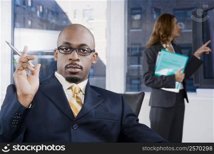 Portrait of a businessman thinking with a businesswoman standing in the background