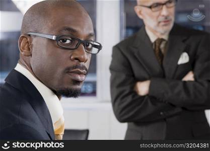 Portrait of a businessman thinking with another businessman standing in the background