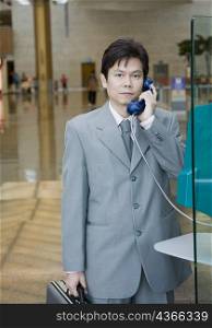 Portrait of a businessman using a pay phone