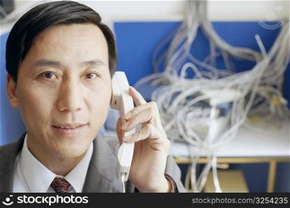 Portrait of a businessman using a telephone in a server room