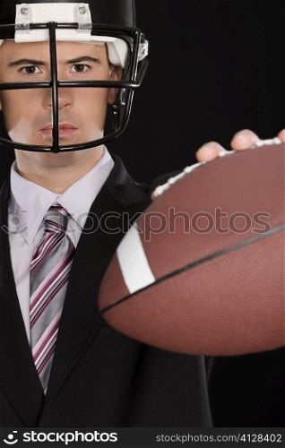 Portrait of a businessman wearing a football helmet and holding an American football