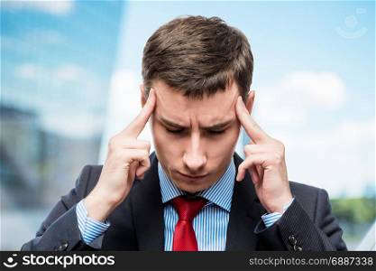 Portrait of a businessman with a strong headache and troubles in business in office