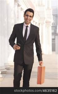 Portrait of a businessman with suitcase smiling , INDIA , DELHI