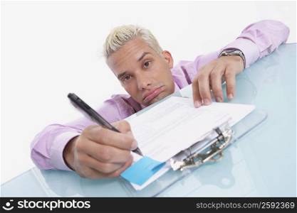 Portrait of a businessman writing on a sheet of paper and looking sad