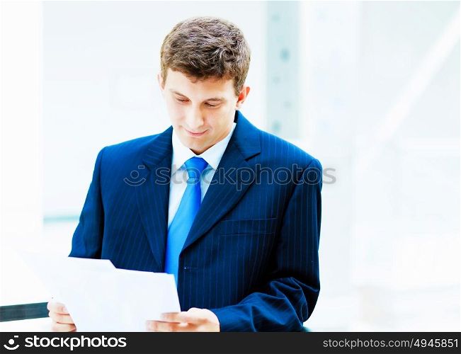 portrait of a businessman.... Young businessman in suit working in bright office, standing