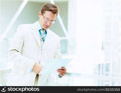 portrait of a businessman.... Young businessman in suit working in bright office, standing