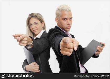 Portrait of a businesswoman and a businessman standing back to back and pointing