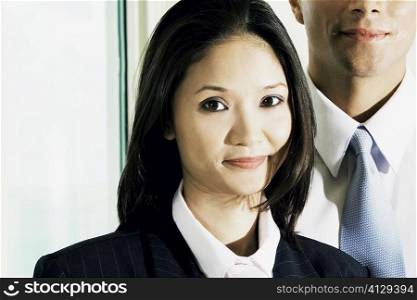 Portrait of a businesswoman and a businessman standing behind her