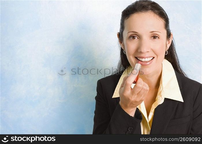 Portrait of a businesswoman applying lipstick on her lips