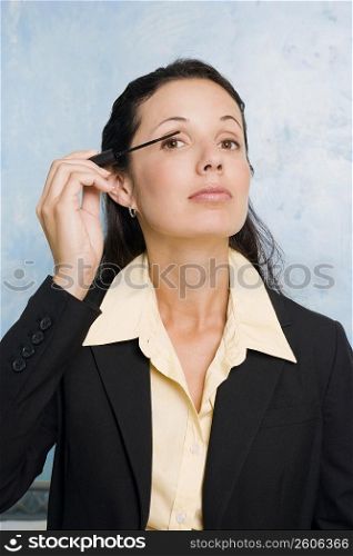 Portrait of a businesswoman applying mascara on her eyes