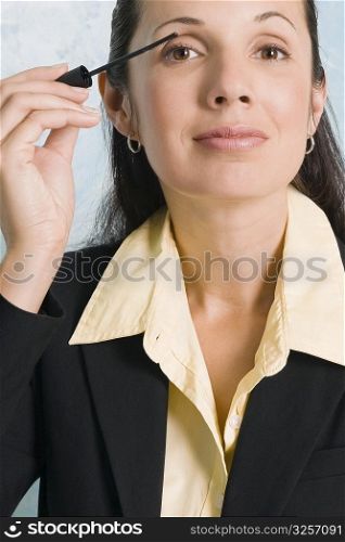 Portrait of a businesswoman applying mascara on her eyes