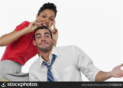 Portrait of a businesswoman gesturing behind a businessman and smiling
