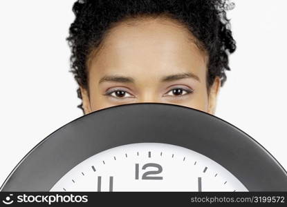 Portrait of a businesswoman hiding her face behind a clock