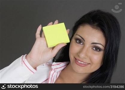 Portrait of a businesswoman holding a blank adhesive note and smiling