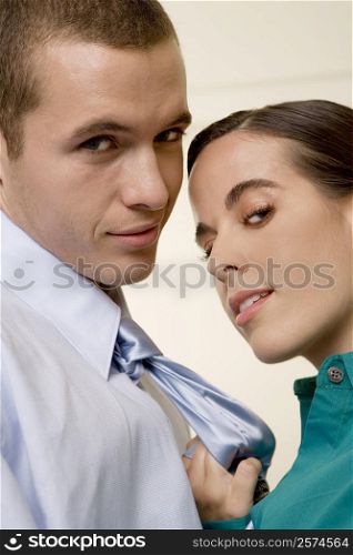 Portrait of a businesswoman holding a businessman by his tie