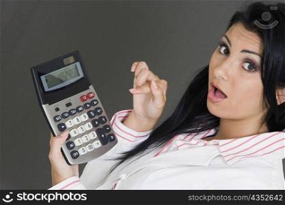 Portrait of a businesswoman holding a calculator and pointing at it