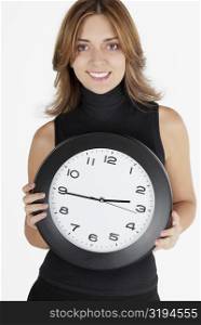 Portrait of a businesswoman holding a clock and smiling