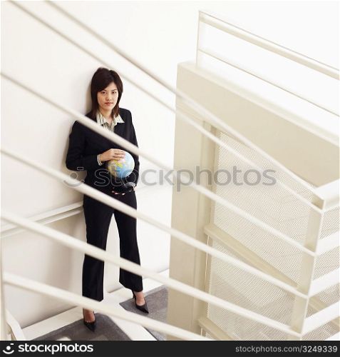 Portrait of a businesswoman holding a globe and posing