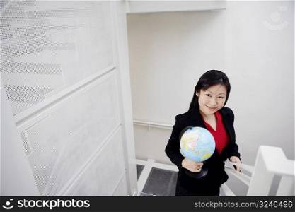 Portrait of a businesswoman holding a globe and smiling