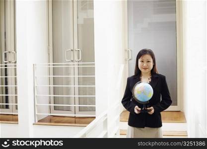 Portrait of a businesswoman holding a globe and smiling