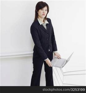 Portrait of a businesswoman holding a laptop and posing