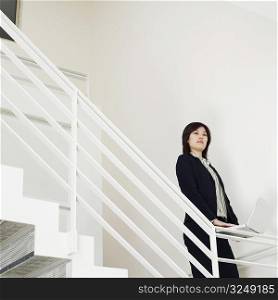 Portrait of a businesswoman holding a laptop on the staircase