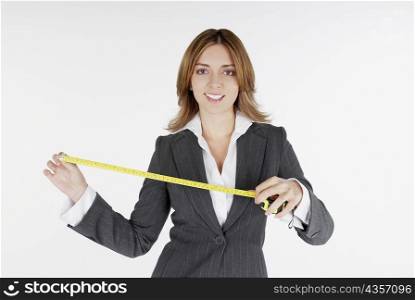 Portrait of a businesswoman holding a measuring tape and smiling