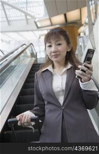 Portrait of a businesswoman holding a mobile phone and a suitcase