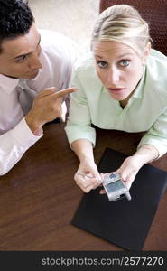 Portrait of a businesswoman holding a mobile phone with a businessman beside her