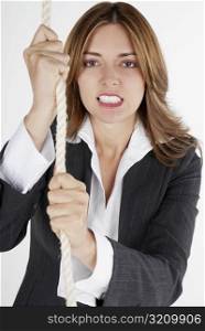 Portrait of a businesswoman holding a rope and clenching her teeth