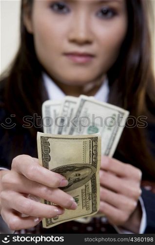 Portrait of a businesswoman holding one hundred dollar bills