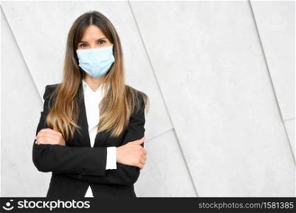 Portrait of a Businesswoman in suit, standing in street wearing face mask looking at camera. High quality photo. Portrait of a Businesswoman in suit, standing in street wearing face mask looking at camera.