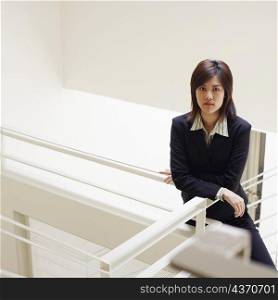 Portrait of a businesswoman leaning over a staircase and posing