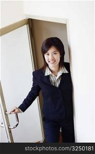 Portrait of a businesswoman opening a door and smiling