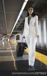 Portrait of a businesswoman pulling her luggage at a subway station