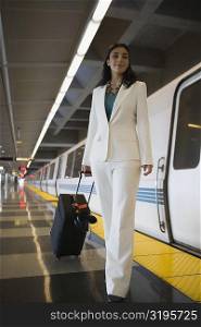 Portrait of a businesswoman pulling her luggage at a subway station and smiling