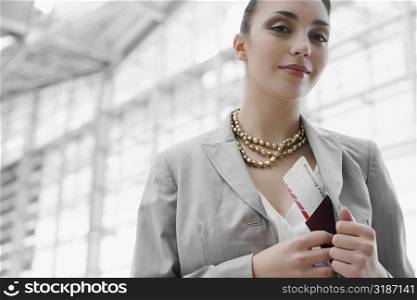 Portrait of a businesswoman putting a passport with an airplane ticket in her coat&acute;s pocket