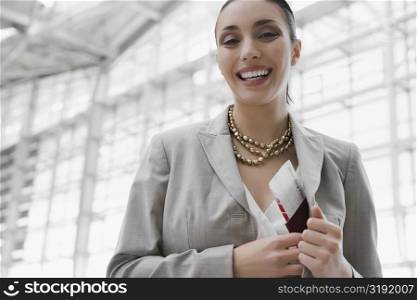 Portrait of a businesswoman putting a passport with an airplane ticket in her coat&acute;s pocket
