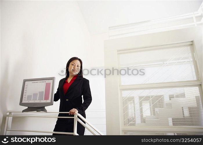 Portrait of a businesswoman showing a growth chart and smiling